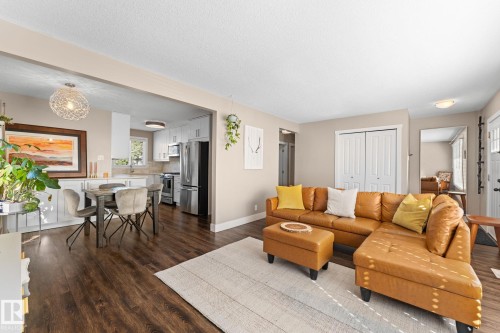 Laminate flooring throughout, bright lighting, white kitchen cabinetry, stainless steel appliances, and a built-in kitchen sink - 6108 102 Avenue Nw, Edmonton, AB 