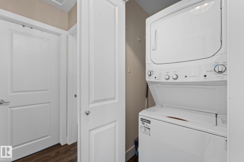 Stacked washer and dryer unit, laminate flooring, and white interior doors - 6108 102 Avenue Nw, Edmonton, AB 