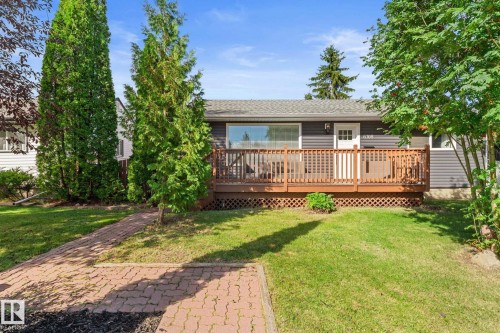 Exterior featuring a wood deck, dark gray siding, and a white entrance door - 6108 102 Avenue Nw, Edmonton, AB 