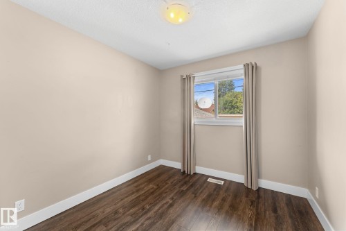 Laminate flooring, neutral wall tones, white trim, window with natural light, and ceiling-mounted light fixture - 6108 102 Avenue Nw, Edmonton, AB 