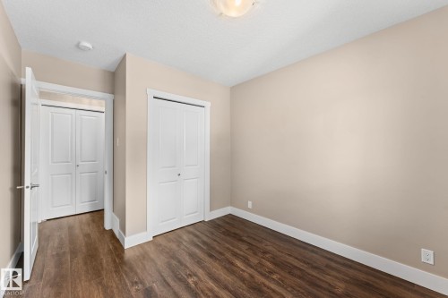 Laminate flooring, neutral wall tones, white trim, window letting in natural light, a ceiling-mounted light fixture, and bi-fold closet doors - 6108 102 Avenue Nw, Edmonton, AB 