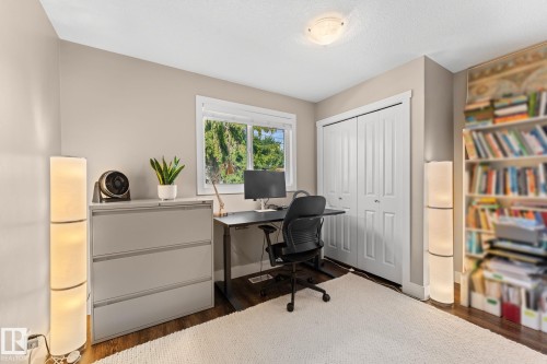 Laminate flooring, neutral wall tones, white trim, window letting in natural light, a ceiling-mounted light fixture, and bi-fold closet doors - 6108 102 Avenue Nw, Edmonton, AB 