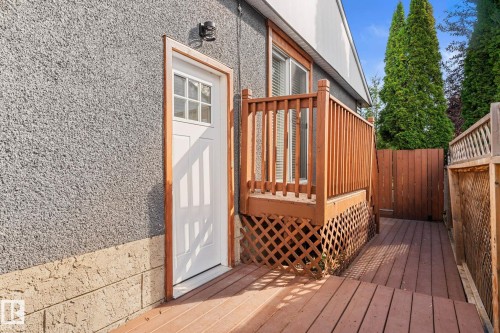 Wood-finish deck with privacy fencing, lattice skirting, and a transom-style entry door for the basement suite - 6108 102 Avenue Nw, Edmonton, AB 