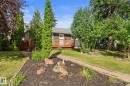 Exterior featuring a wood deck, dark gray siding, and a white entrance door - 6108 102 Avenue Nw, Edmonton, AB 