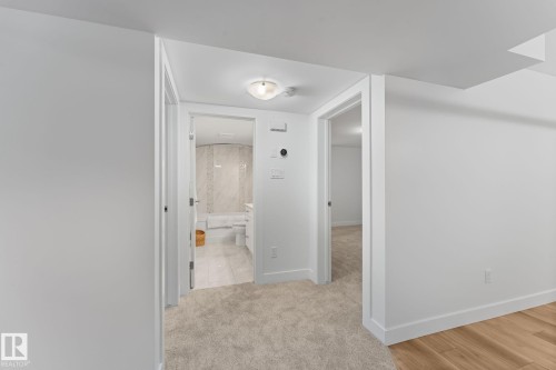 Carpeted hallway with a flush-mount light fixture and white trim - 6108 102 Avenue Nw, Edmonton, AB 