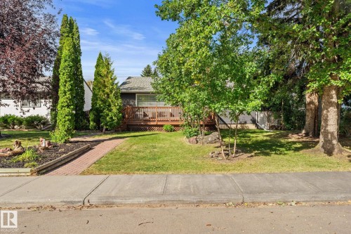 Exterior featuring a wood deck, dark gray siding, and a white entrance door - 6108 102 Avenue Nw, Edmonton, AB 