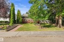 Exterior featuring a wood deck, dark gray siding, and a white entrance door - 6108 102 Avenue Nw, Edmonton, AB 