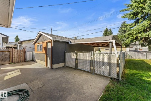 Detached single garage, single covered carport, concrete driveway, chain-link fencing, and mature trees - 6108 102 Avenue Nw, Edmonton, AB 