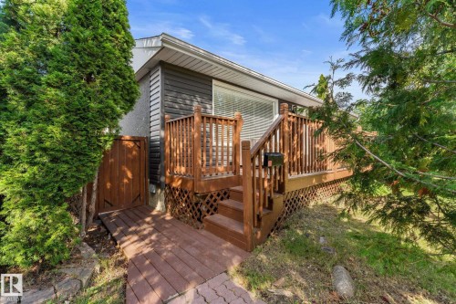Exterior featuring a wood deck, dark gray siding, and a white entrance door - 6108 102 Avenue Nw, Edmonton, AB 