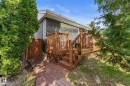 Exterior featuring a wood deck, dark gray siding, and a white entrance door - 6108 102 Avenue Nw, Edmonton, AB 