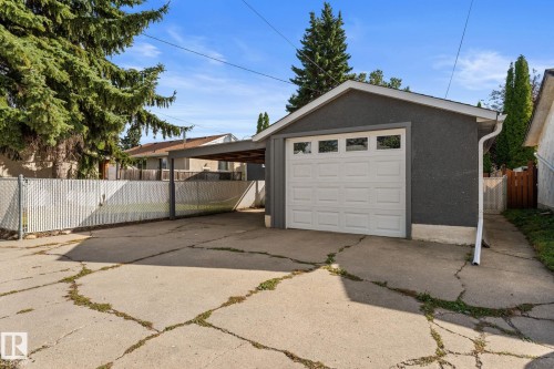 Detached single garage, single covered carport, concrete driveway, chain-link fencing, and mature trees - 6108 102 Avenue Nw, Edmonton, AB 
