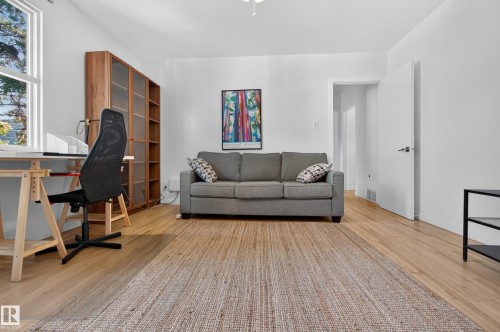 Light wood-finish flooring, built-in wooden shelving with glass doors, and a white interior door with a brushed nickel handle - 6807 112A Street Nw, Edmonton, AB 