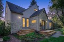 Stucco and stone veneer exterior with a dark shingle roof, featuring multiple wood decks and exterior lighting fixtures - 6807 112A Street Nw, Edmonton, AB 