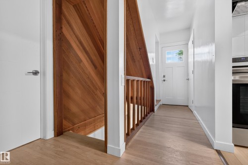 Wood-finish flooring throughout, white interior doors, wood staircase with balustrade, and modern stainless steel appliances - 6807 112A Street Nw, Edmonton, AB 