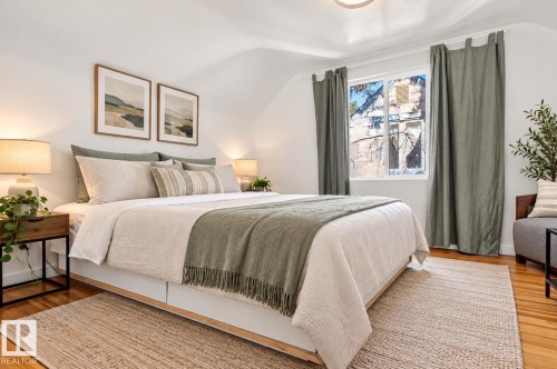 Hardwood flooring, painted white walls, recessed window with curtain rods, and sloped ceiling - 6807 112A Street Nw, Edmonton, AB 