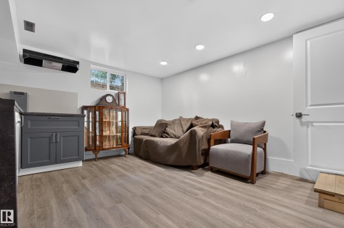 Recessed lighting, wood-finish flooring, white walls, built-in lower cabinetry with dark countertop, and a white two-panel door - 6807 112A Street Nw, Edmonton, AB 