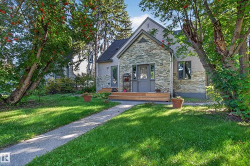Stone veneer facade with a gabled roof, complemented by mature trees and a manicured lawn - 6807 112A Street Nw, Edmonton, AB 