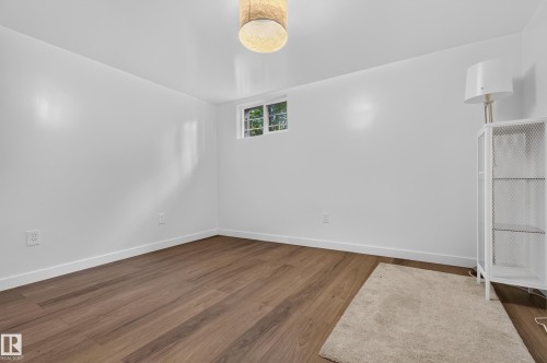 Recessed window, wood-finish flooring, white baseboards, and a drum pendant light fixture - 6807 112A Street Nw, Edmonton, AB 