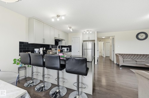 Kitchen featuring white cabinetry, black subway tile backsplash, stainless steel appliances, and a peninsula with seating - 941 Ebbers Crescent Nw, Edmonton, AB 