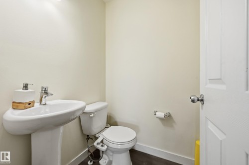 Pedestal sink with chrome-finish faucet, white toilet, and wood-finish flooring - 941 Ebbers Crescent Nw, Edmonton, AB 