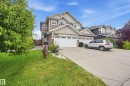 Two-story residence featuring a multi-gable roofline, neutral siding, stone accents, and a dual-bay garage with white doors - 941 Ebbers Crescent Nw, Edmonton, AB 