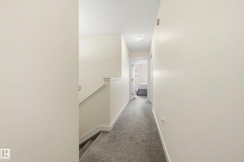 Carpeted hallway with painted walls and a flush-mount light fixture - 941 Ebbers Crescent Nw, Edmonton, AB 