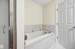 Built-in bathtub with tiled surround, chrome fixtures, and complementary tiled flooring - 