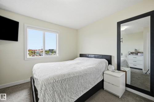 Wall-mounted television, large framed mirror, and a window with white trim - 941 Ebbers Crescent Nw, Edmonton, AB 
