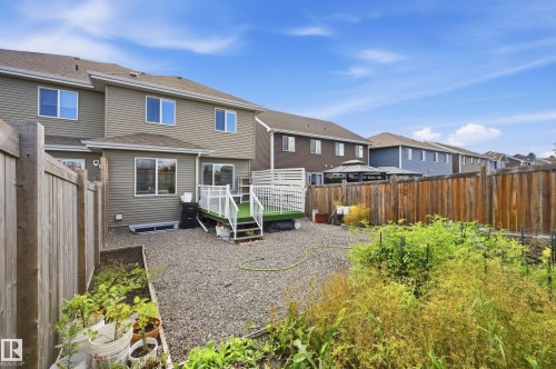 Expansive gravel backyard featuring a wooden privacy fence, raised planter beds, and a multi-level deck with white railings - 941 Ebbers Crescent Nw, Edmonton, AB 