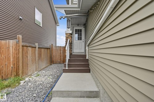 Entry with concrete steps and landing, a white entry door with glass panels, and a stone-clad pillar - 941 Ebbers Crescent Nw, Edmonton, AB 