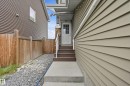 Entry with concrete steps and landing, a white entry door with glass panels, and a stone-clad pillar - 941 Ebbers Crescent Nw, Edmonton, AB 
