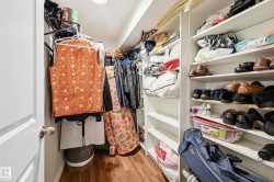 Walk-in closet featuring wood-finish flooring, white shelving, and hanging storage - 