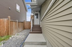 Entry with concrete steps and landing, a white entry door with glass panels, and a stone-clad pillar - 
