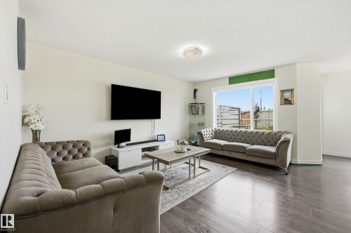 Spacious living area featuring wood-finish flooring, a large window, and light-toned walls - 941 Ebbers Crescent Nw, Edmonton, AB 