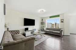 Spacious living area featuring wood-finish flooring, a large window, and light-toned walls - 