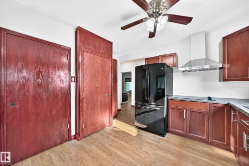 Kitchen featuring wood-finish flooring, dark wood cabinetry, and light-toned countertops - 9719 71 Avenue Nw, Edmonton, AB - Indoor Photo Showing Kitchen