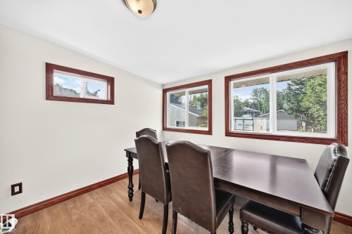 Bright room featuring three windows with wood trim, wood-finish flooring, and a ceiling-mounted light fixture - 9719 71 Avenue Nw, Edmonton, AB - Indoor Photo Showing Dining Room