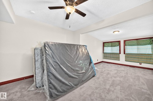 Spacious room featuring light gray carpet, white walls, and dark wood-finish trim - 9719 71 Avenue Nw, Edmonton, AB - Indoor Photo Showing Other Room