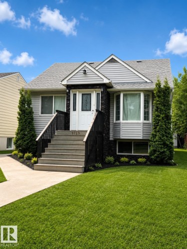 Contemporary split-level residence featuring gray siding and dark stone facade accents - 9719 71 Avenue Nw, Edmonton, AB - Outdoor With Facade