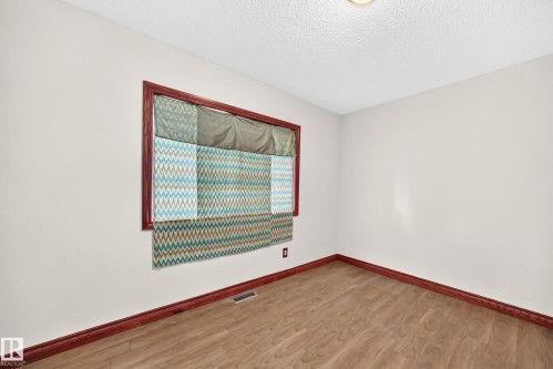 Room featuring light-toned walls, wood-finish flooring, and dark wood trim - 9719 71 Avenue Nw, Edmonton, AB - Indoor Photo Showing Other Room