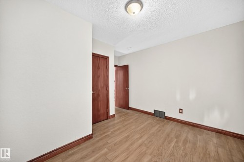 Room featuring wood-finish flooring, light-toned walls, and wood-paneled doors - 9719 71 Avenue Nw, Edmonton, AB - Indoor Photo Showing Other Room