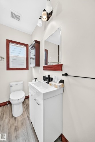 Bathroom featuring a white vanity with integrated sink, black faucet, and rectangular mirror - 9719 71 Avenue Nw, Edmonton, AB - Indoor Photo Showing Bathroom
