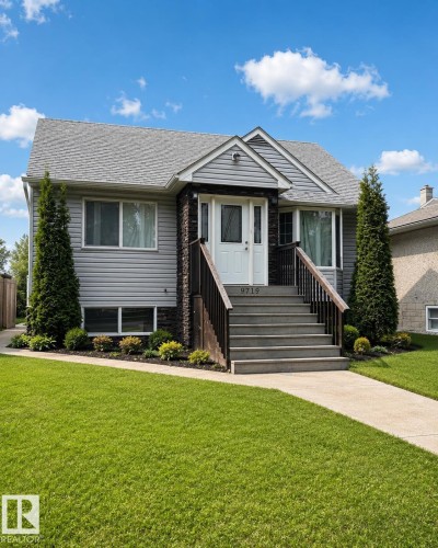 Charming residence featuring gray siding with stone accents, a prominent front staircase with dark railings, a well-maintained lawn, and established perimeter landscaping - 9719 71 Avenue Nw, Edmonton, AB - Outdoor With Facade