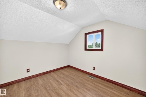 Attic room with wood-finish flooring, light neutral walls, and a window with wood trim - 9719 71 Avenue Nw, Edmonton, AB - Indoor Photo Showing Other Room