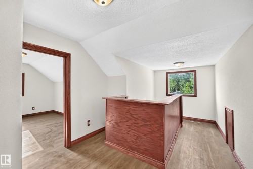 Finished attic space featuring a built-in wood-finish bar, wood-finish flooring, a window with natural light, and a room entry with wood-finish trim - 9719 71 Avenue Nw, Edmonton, AB - Indoor Photo Showing Other Room