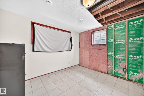 Unfinished basement room featuring exposed framing, insulation, and concrete flooring, offering an opportunity for customization - 9719 71 Avenue Nw, Edmonton, AB - Indoor