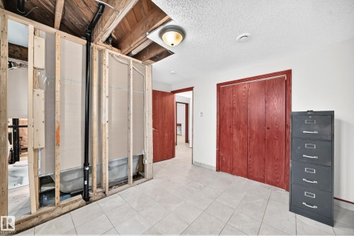 Tiled flooring extends through this area, featuring exposed ceiling joists and framing indicating ongoing renovation - 9719 71 Avenue Nw, Edmonton, AB - Indoor Photo Showing Other Room