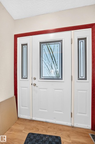 White entry door with decorative glass inserts, flanked by matching sidelights, framed by red trim - 9719 71 Avenue Nw, Edmonton, AB - Indoor Photo Showing Other Room