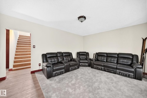 Spacious interior room featuring light wood-finish flooring transitioning to a grey area rug - 9719 71 Avenue Nw, Edmonton, AB - Indoor Photo Showing Living Room