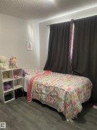 Wood-finish flooring with neutral wall tones and a window featuring dark drapery - 